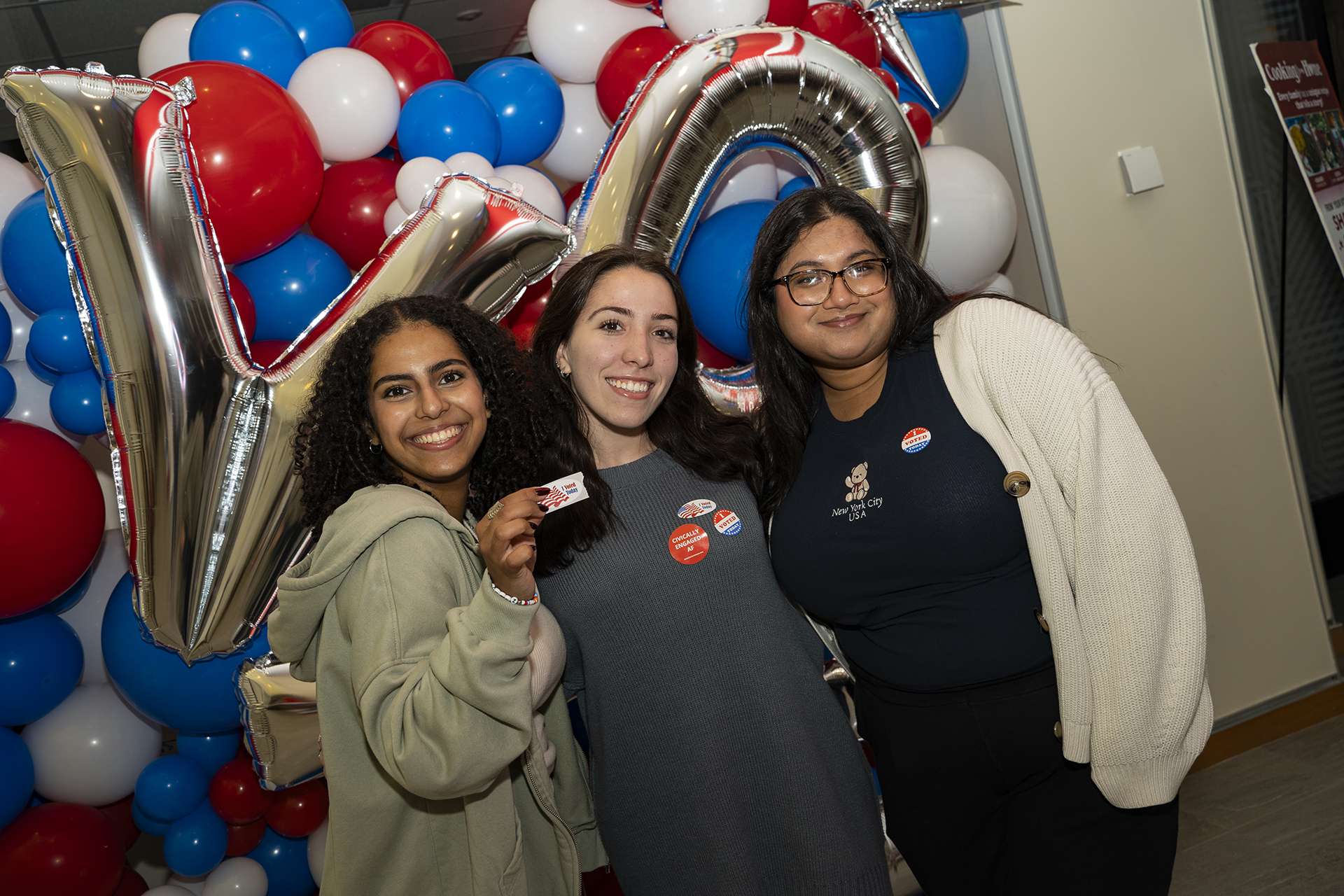 A group of students taking photos on Election Day with balloons and stickers.