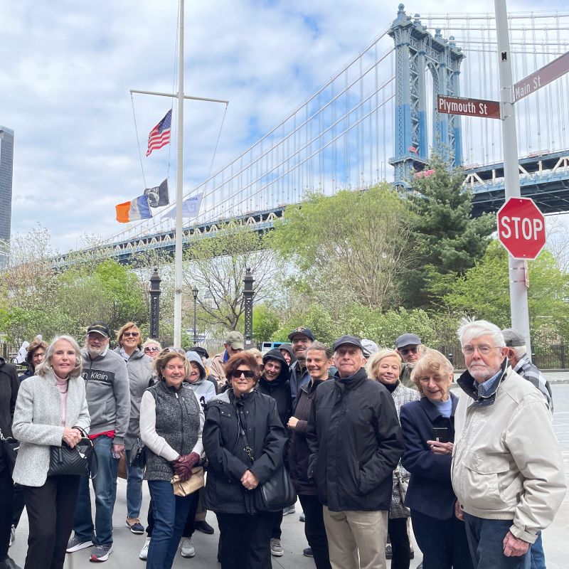 A group of OLLI members posing in front of Manhattan bridge