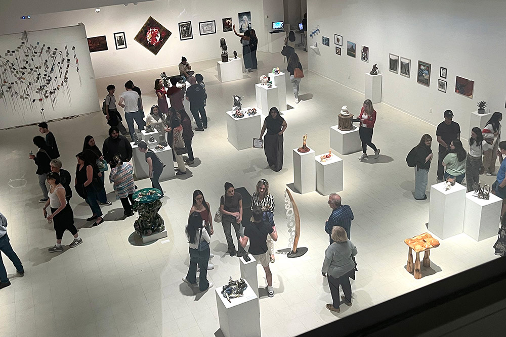 Visitors viewing student artwork displayed in a university gallery exhibition