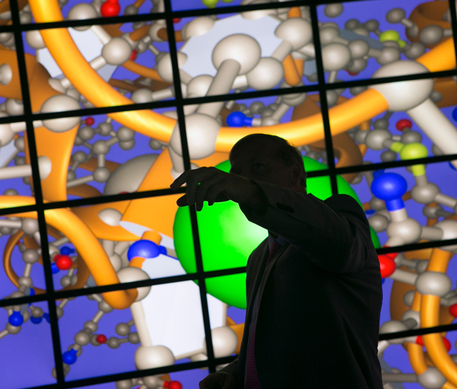 professor pointing at an image of atoms on screen