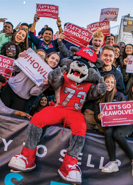 Wolfie Seawolf mascot surrounded by cheering people with signs