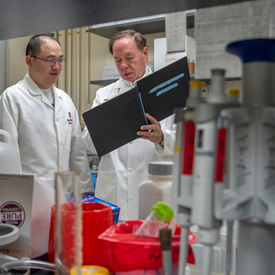 Researchers in white coats look at a folder in a lab