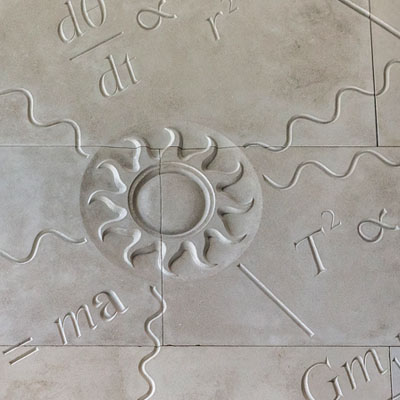 stone engraved with image of sun surrounded by equations