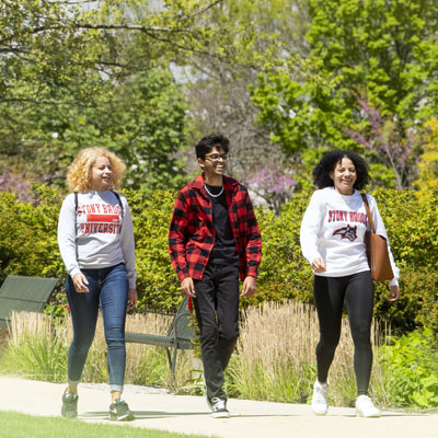 Three students walk along a path in early spring