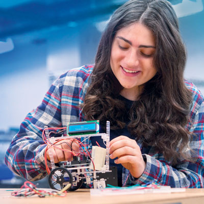 a student works on a small mechanical engineering device
