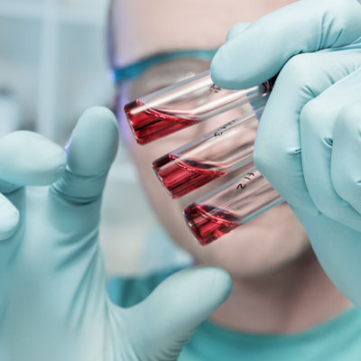 scientists holding tubes with red liquid