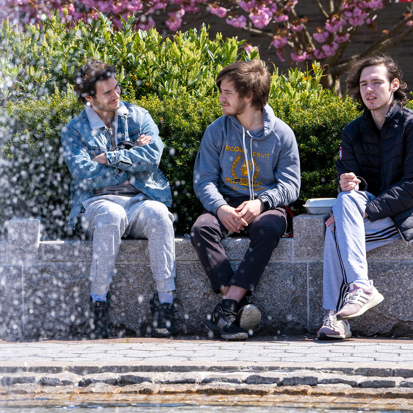 A group of students sitting and talking by the fountain