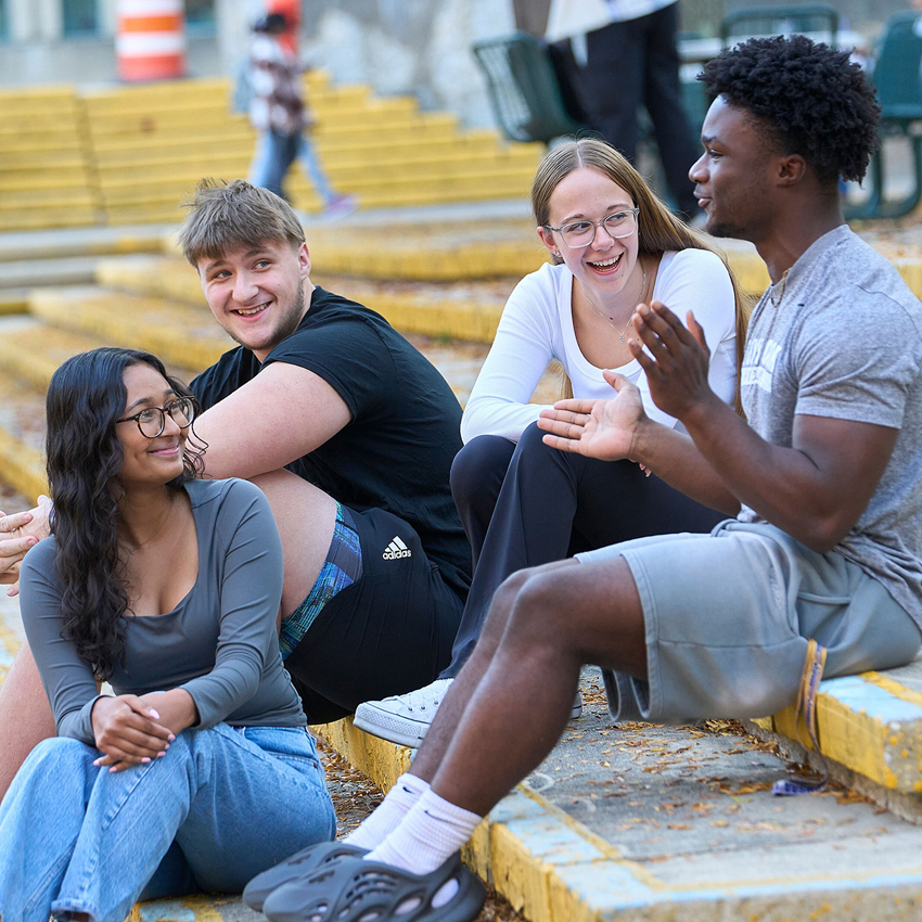 A group of four students sit and chat on stairs