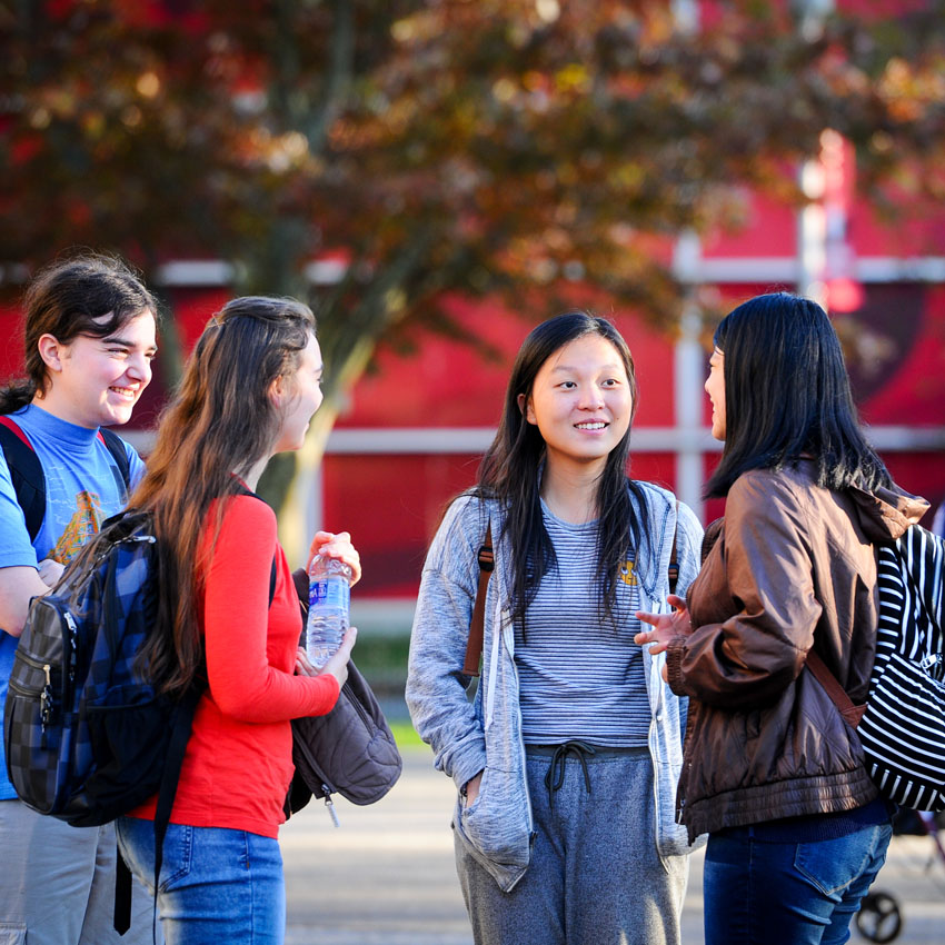 A group of four students standing together and talking