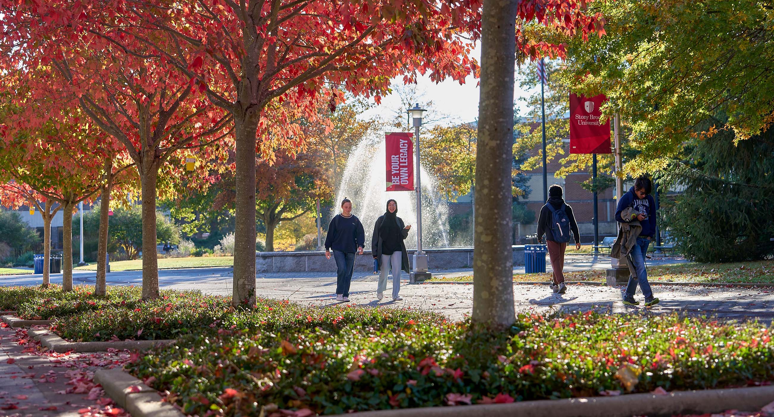 Stony Brook Signage with students walking down the academic mall in fall