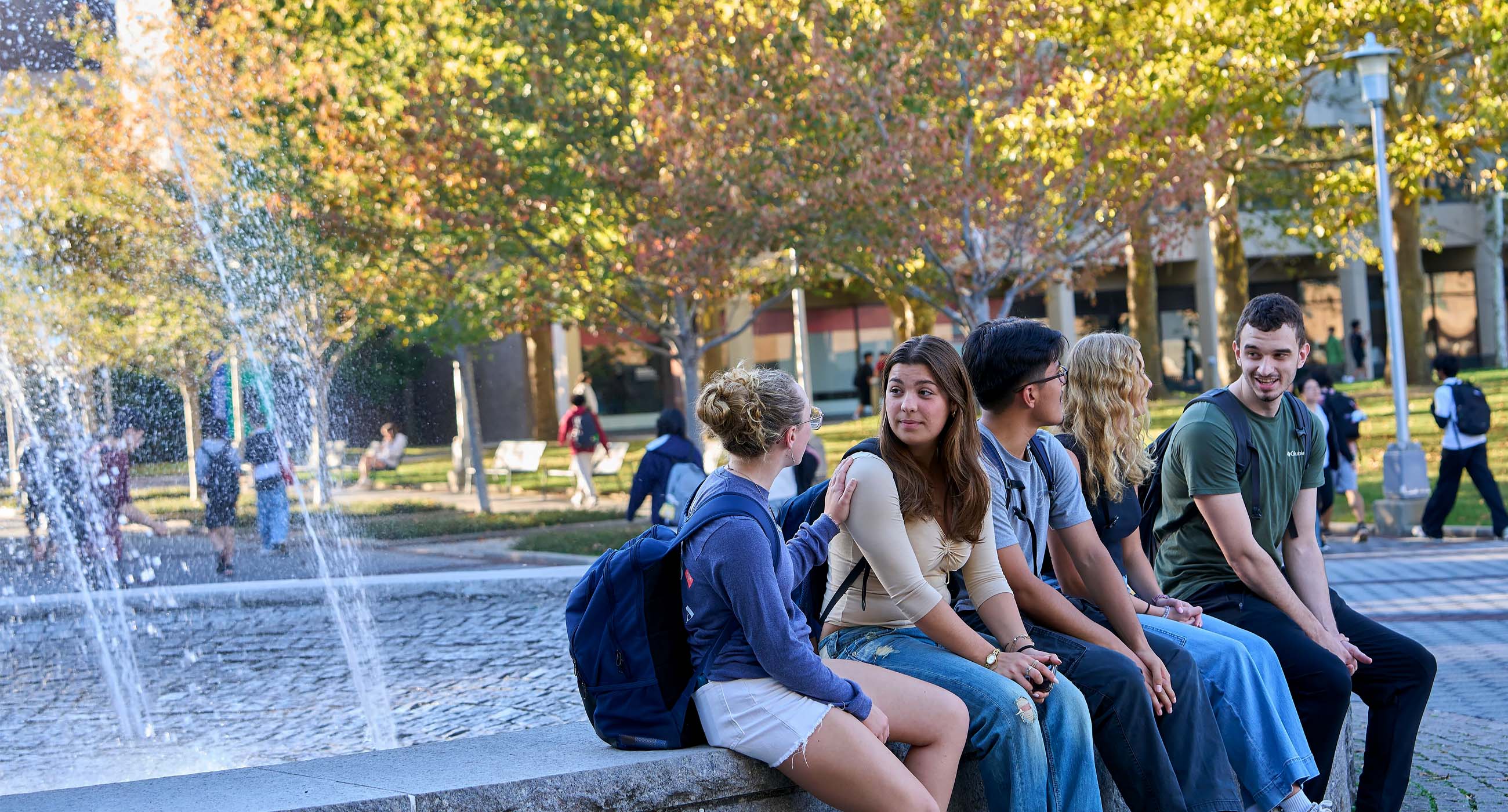 Students sitting on the edge of a fountain talking
