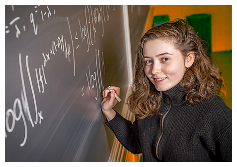 student writing on blackboard