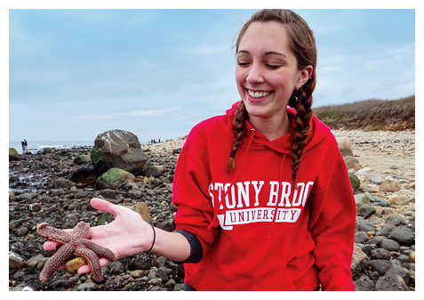 student at beach holding starfish