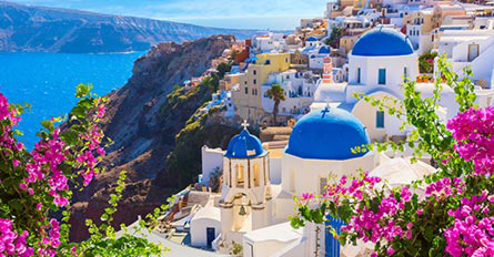 greek town with white building with blue roofs on a mountain by the sea