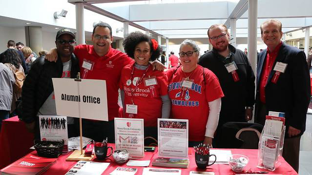 Group of alumni at registration table smiling