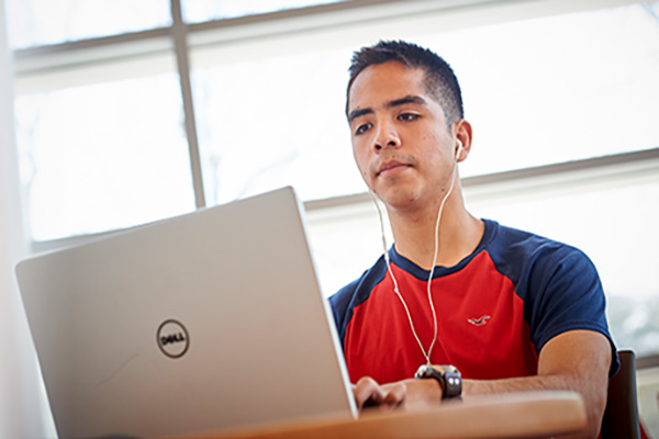 Student using headphones at his laptop