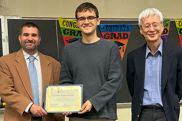 Student standing with AMS faculty holding an award