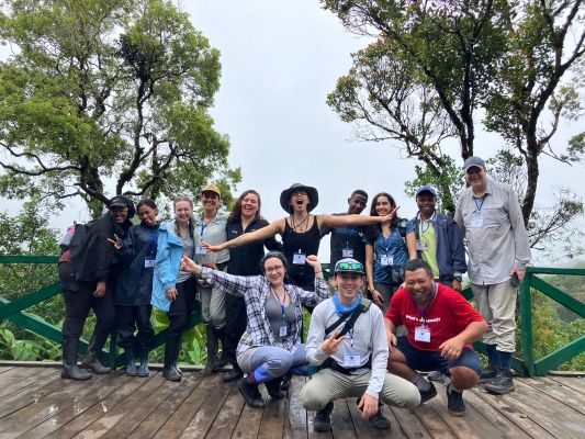 A group of study abroad Madagascar students posing on a desk overlooking a rain forest