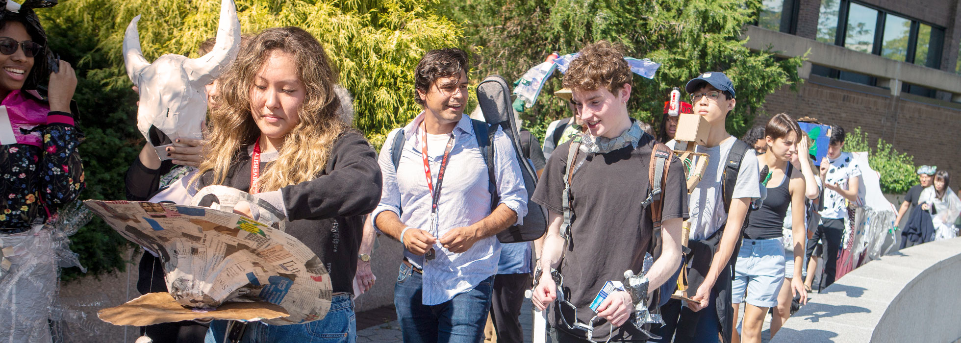 Students dressed in a variety of costumes walking cheerfully across the campus.