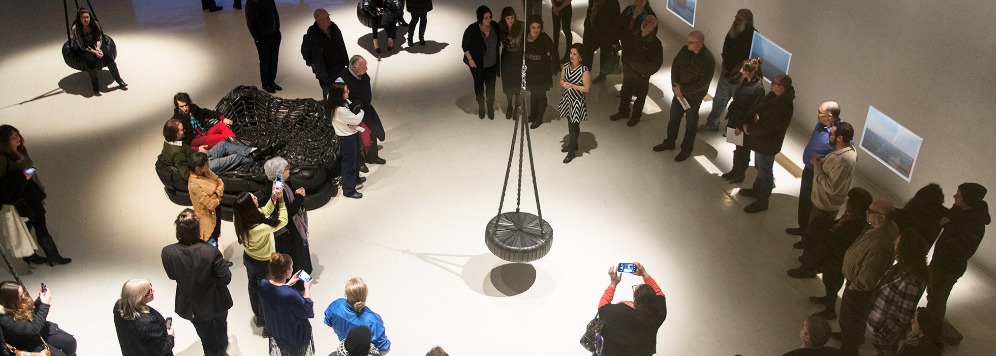 Many audience members are listening intently to the person presenting artworks at the Paul W. Zuccaire Gallery.