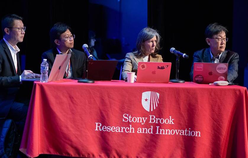 Group of people at a table with red tablecloth that says Stony Brook Research and Innovation