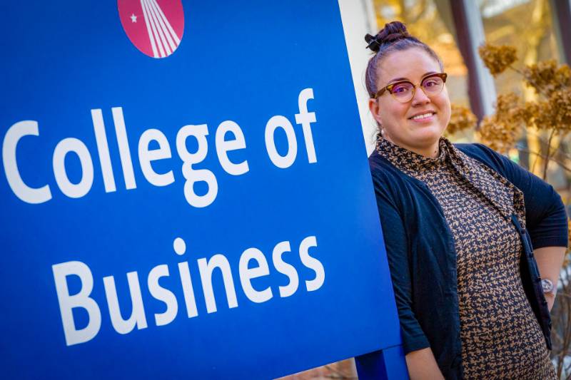 Margret next to college of business sign