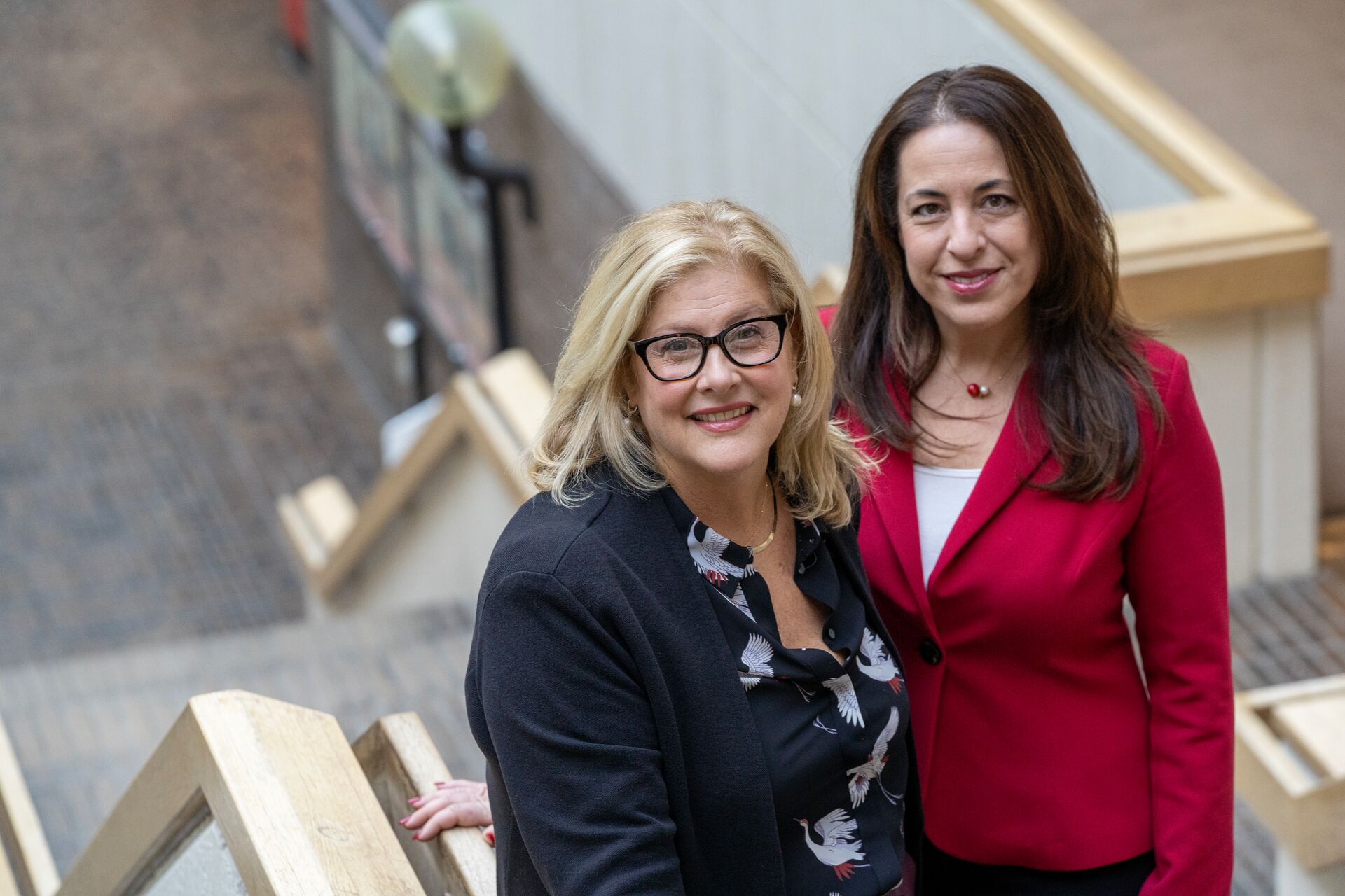 Two caucasian woman, one with blonde hair and one brunette, standing on a staircase