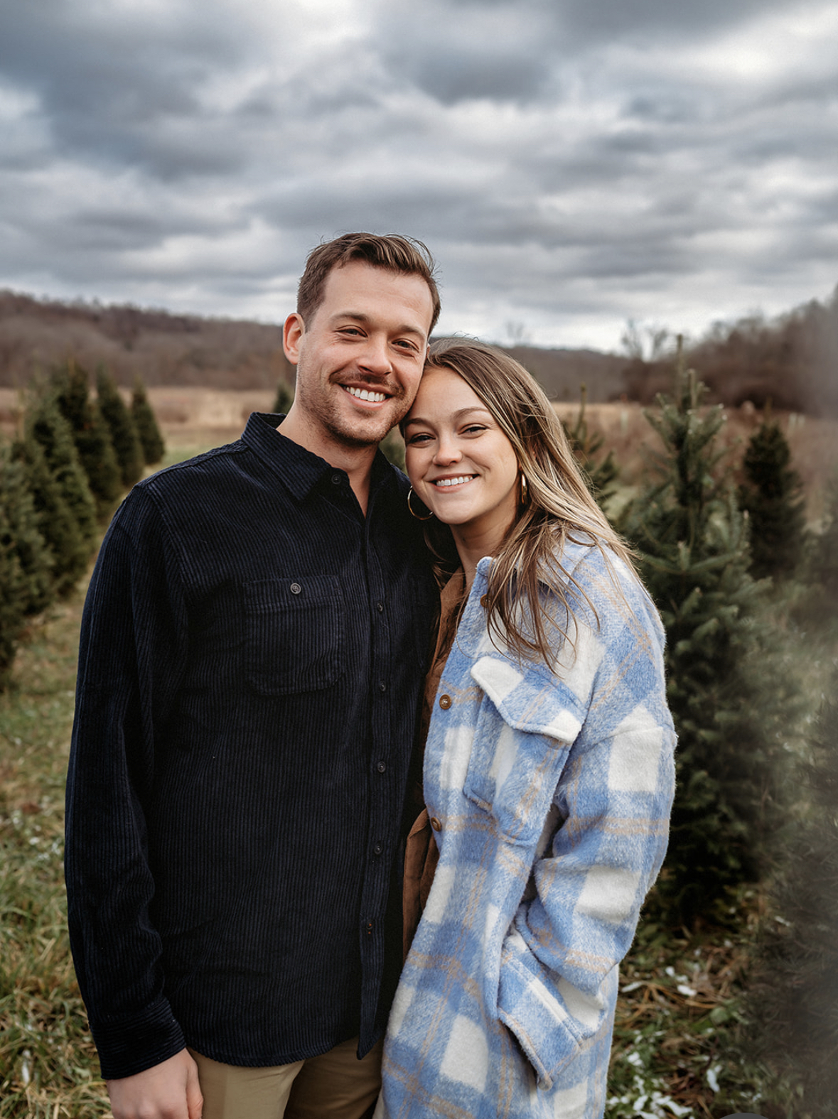 Caucasian couple (male and female) hugging in a field of Christmas tree farm