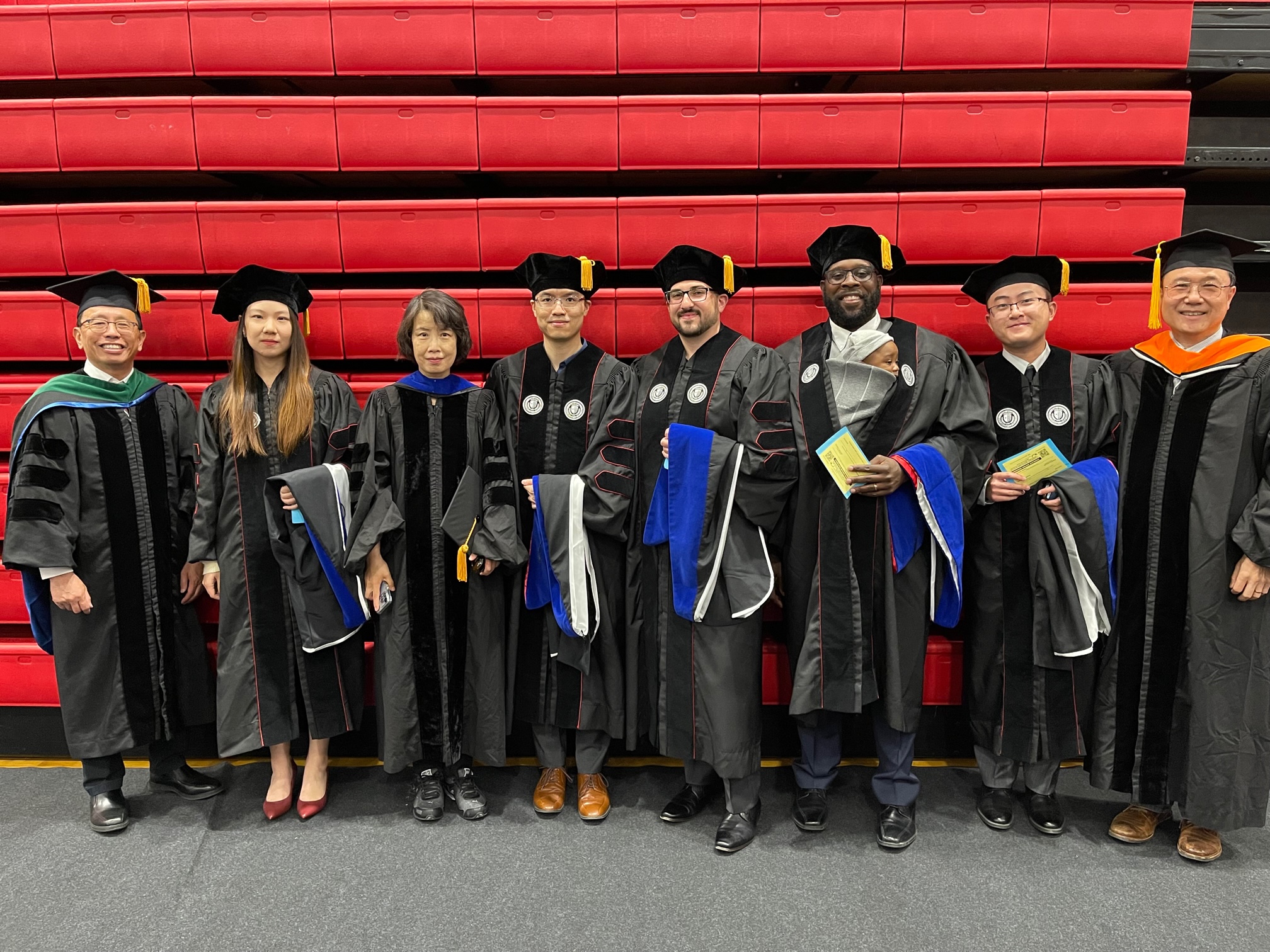 PhD hooding ceremony with four faculty members and four students