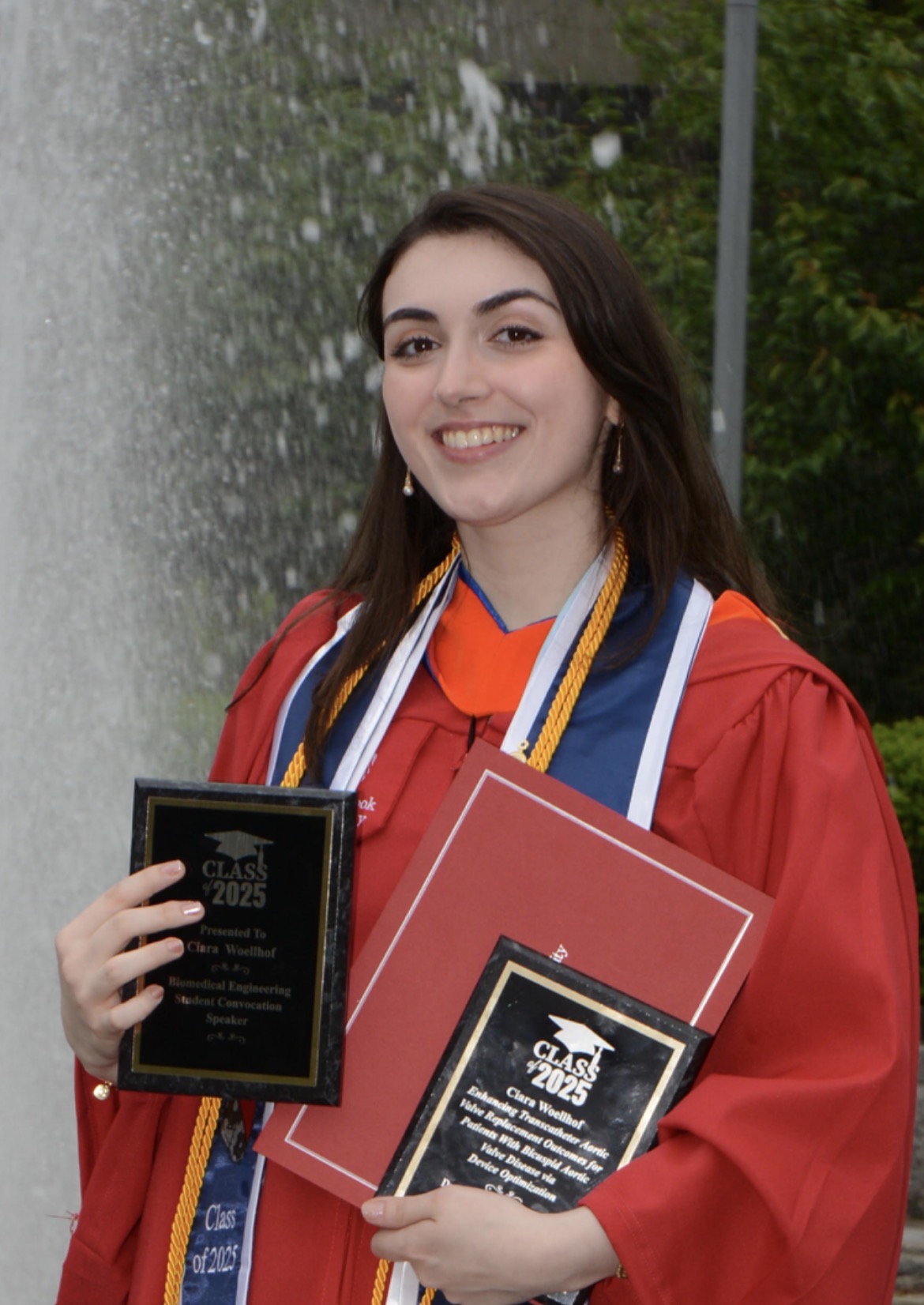Ciara posing with her award in graduation attire