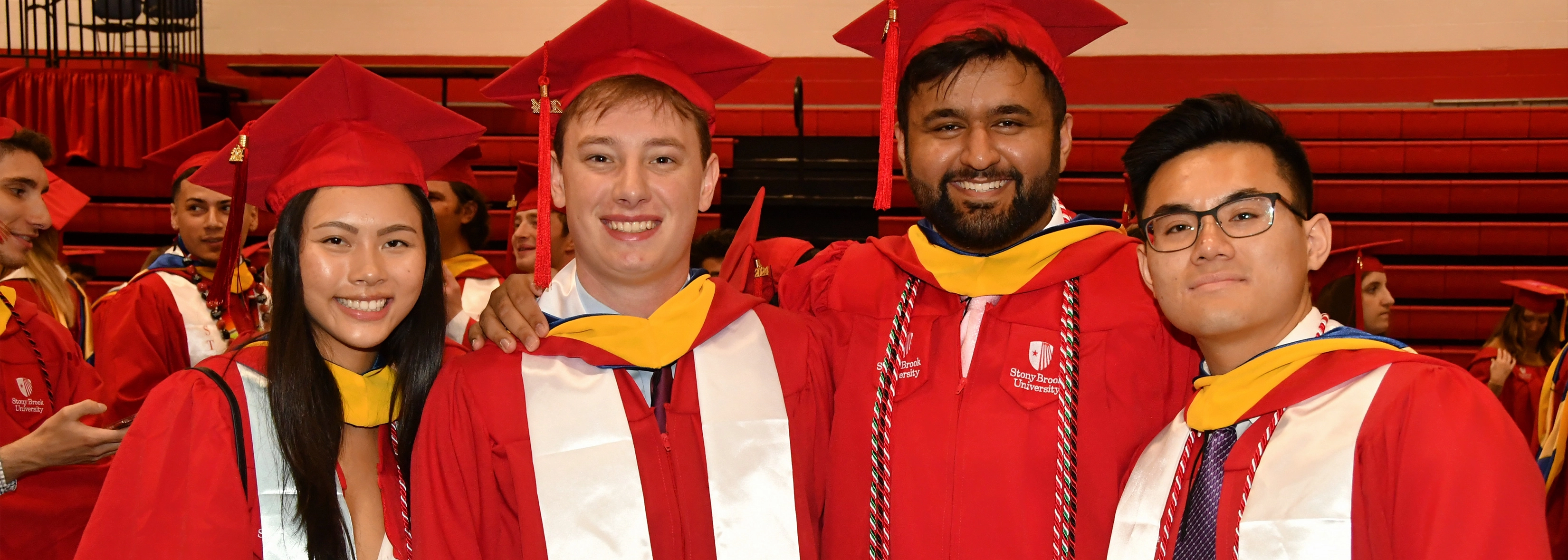 four students in college of business regalia on convocation day