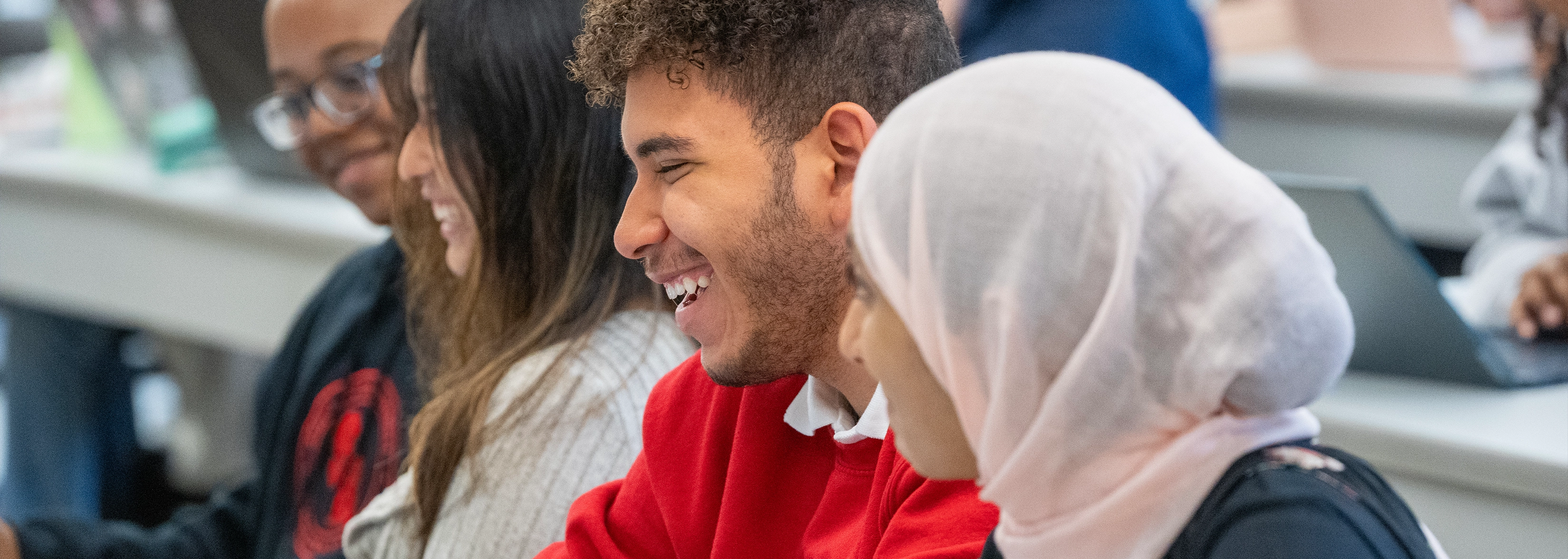 Four students sitting together, engaged in conversation in a classroom