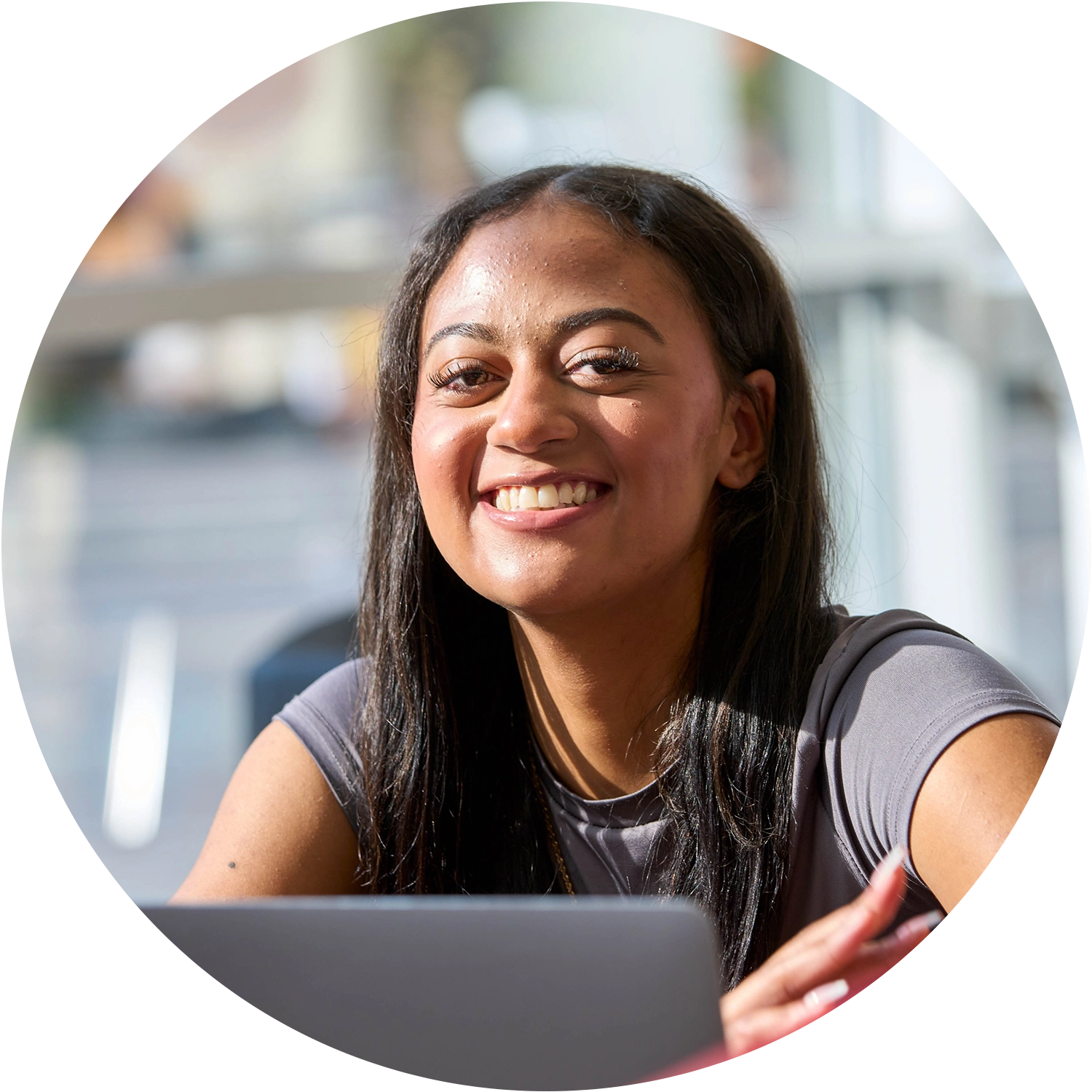 Smiling person sitting at a table with a laptop indoors