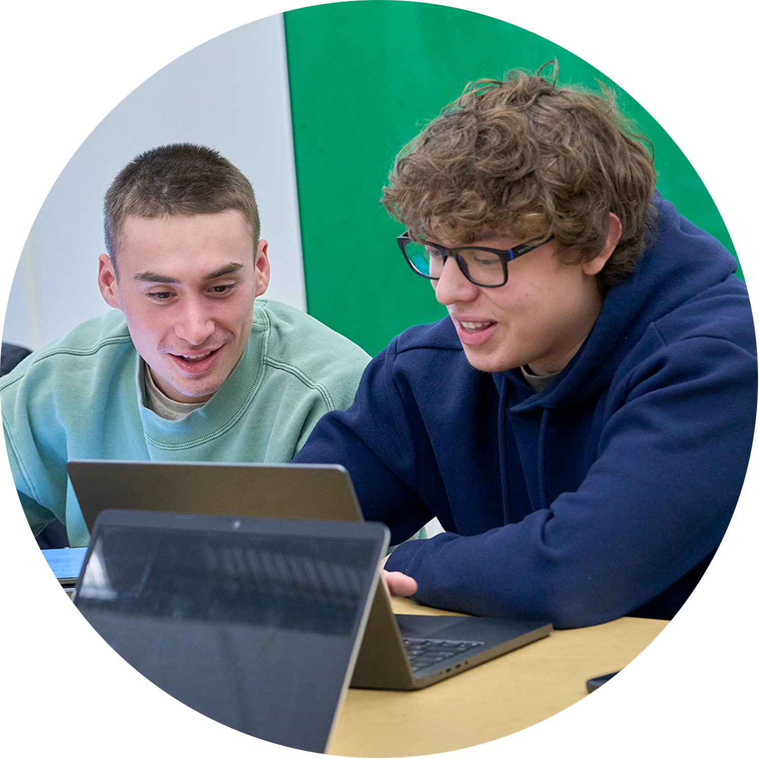 Two student collaborating with a laptop in between them