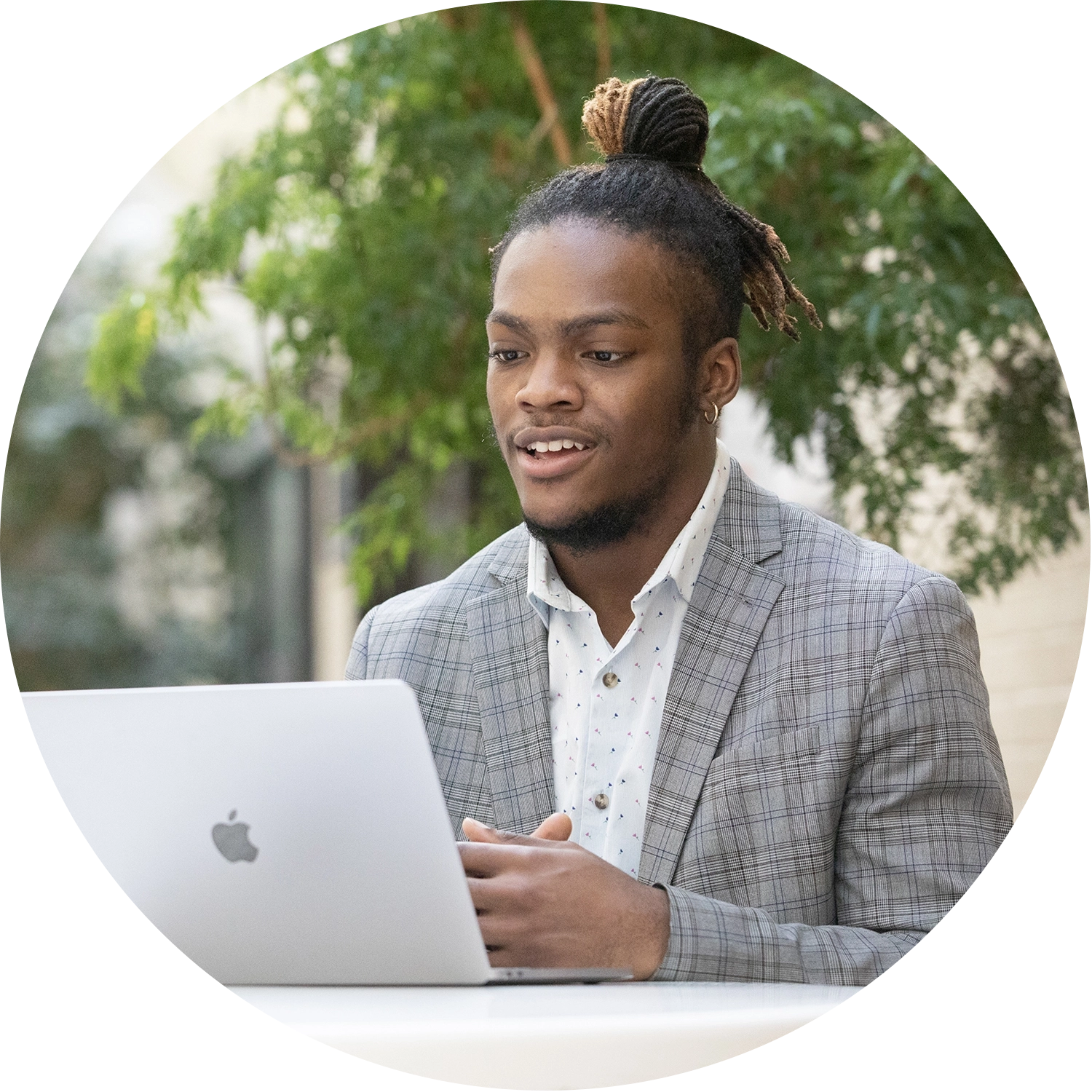 A man in a plaid jacket using a laptop outdoors