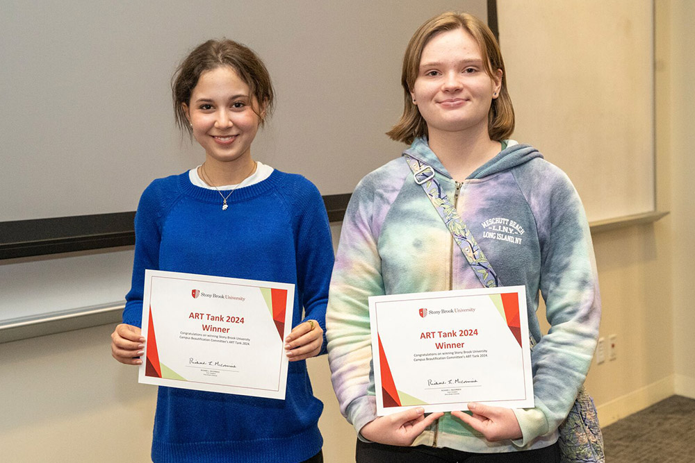 Two young female artists holding certificates for winning ART Tank