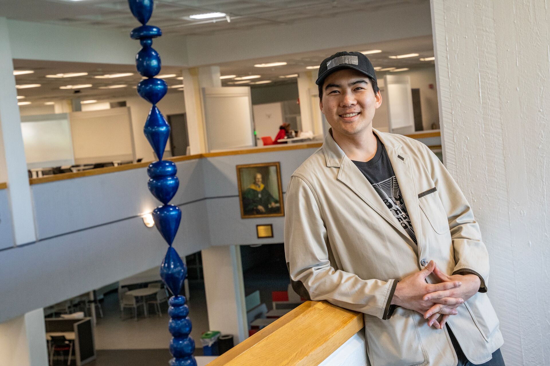 student standing in front of water droplet sculpture hanging from thr ceiling