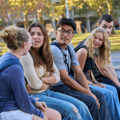 A group of students sitting in a straight line having a chat between classes