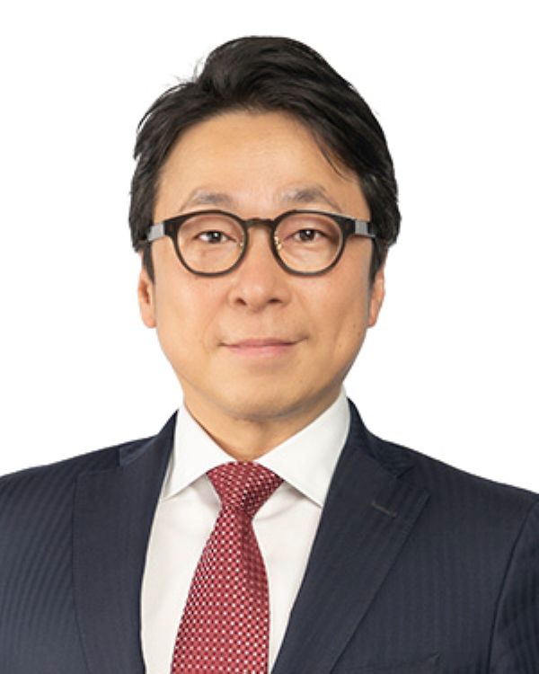 Professional portrait of an individual wearing glasses, a dark suit, and a red patterned tie.