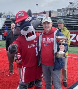 SBU mascot Wolfie with Paul Kelton holding the Dean's cup,