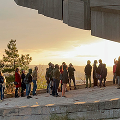 A group of people standing together on a concrete wall, smiling and enjoying the outdoors.