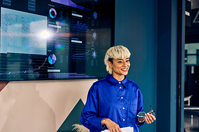 Woman with short blond hair presenting in front of large screen