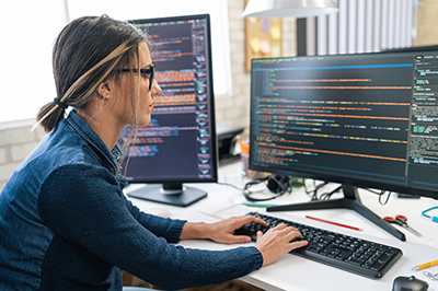 woman in front of multiple screens with code