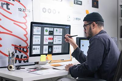 man with beard in front of computer with images
