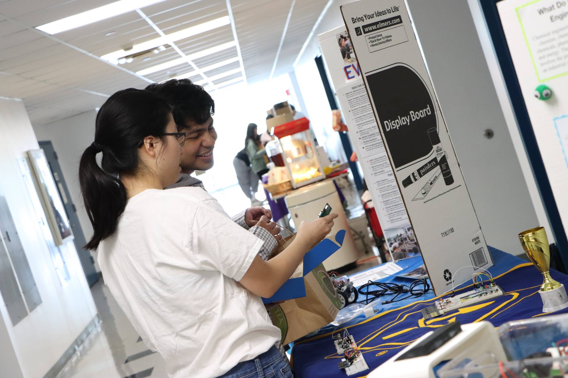 Two students looking at items on a table at a club fair.