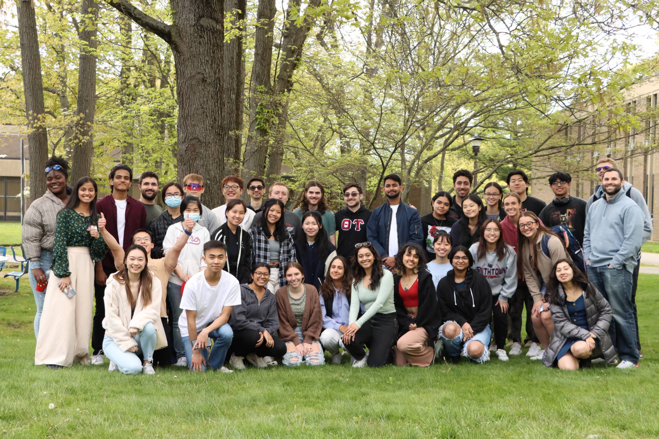 Group of students standing and kneeling outside on a overcast day.