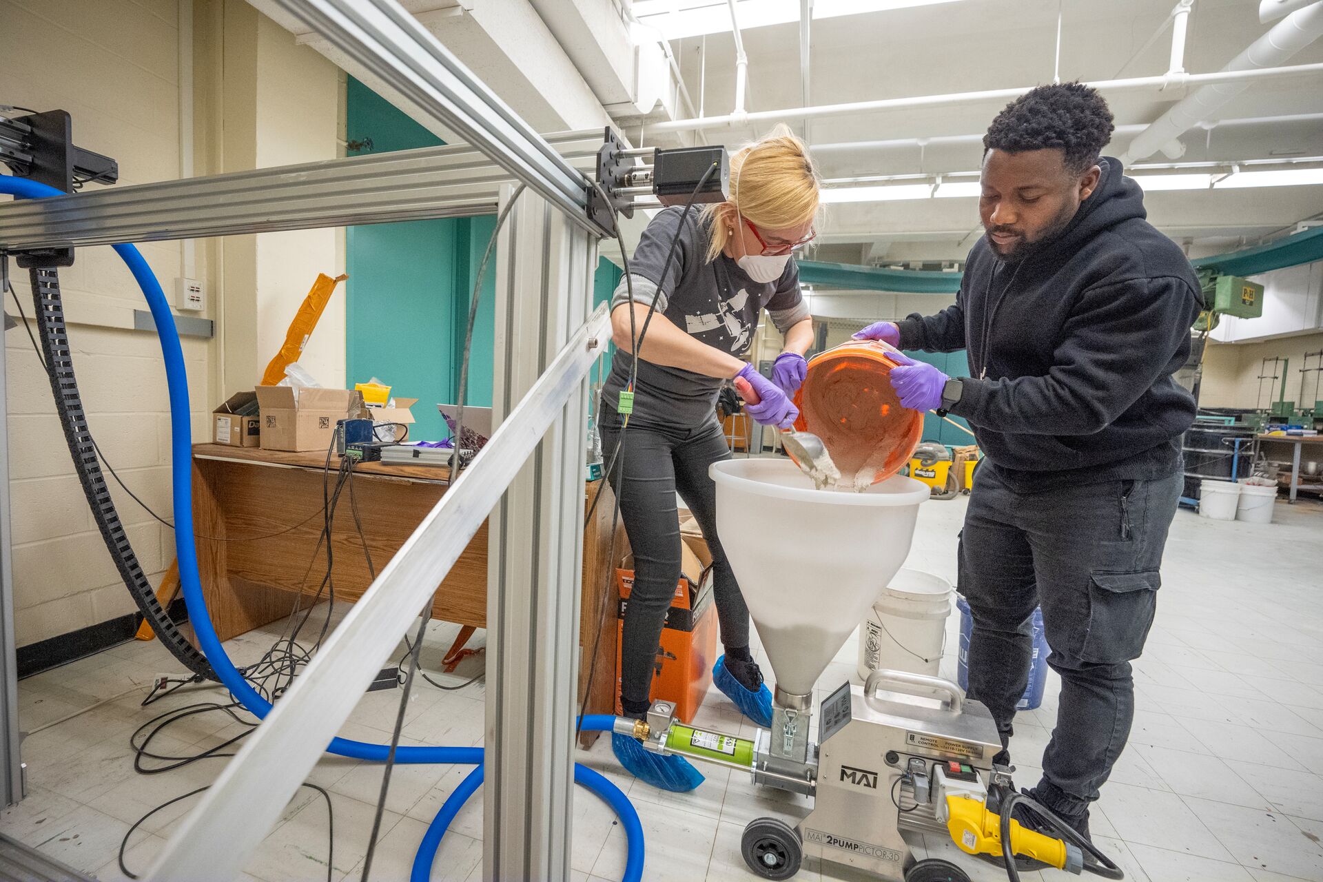 Professor working with student to pour concrete.