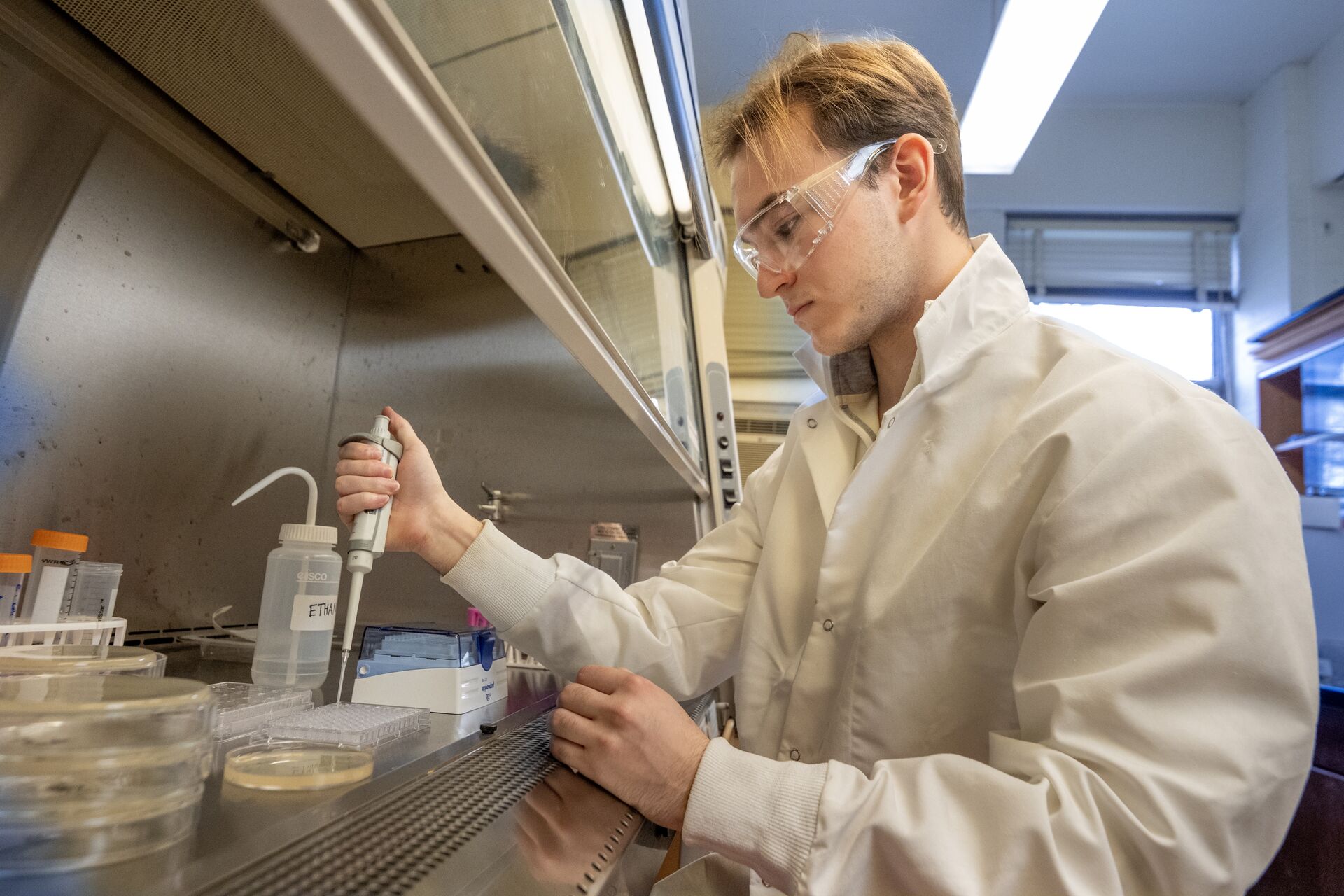 Student in lab coat working with pipets.