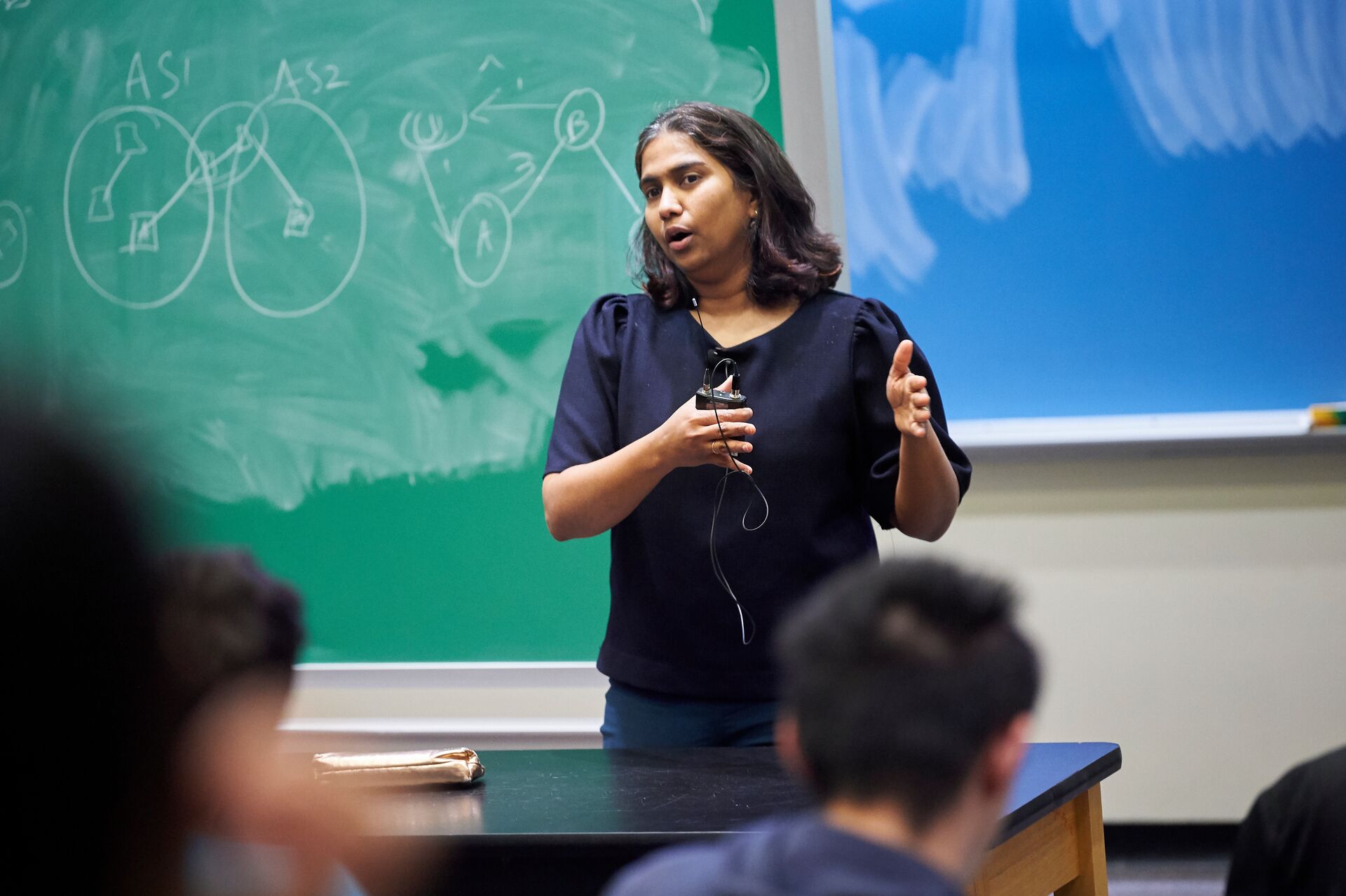 Professor teaching with information written on a chalkboard behind her.
