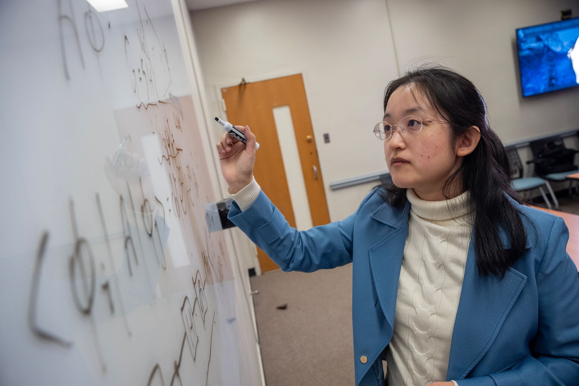 Professor writing equations on a whiteboard.